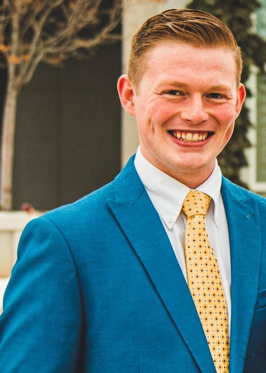 Brady Allred, wearing a blue suit and smiling.