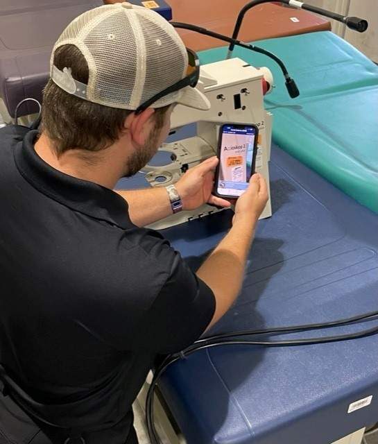 A UF employee scanning an asset tag with a phone in the surplus warehouse.